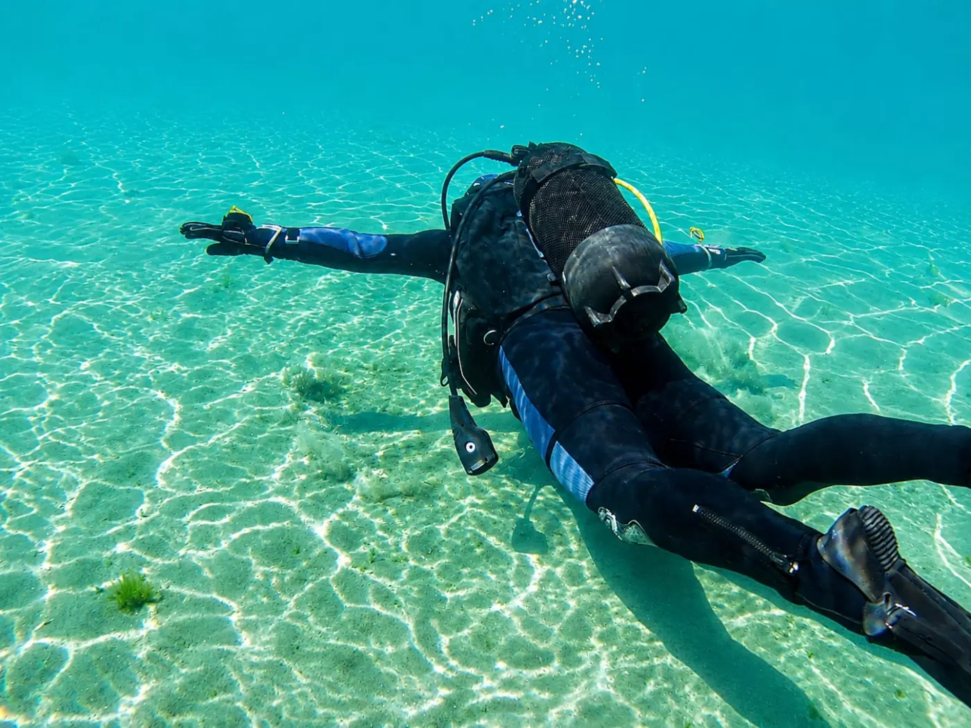 A diver glides over the sandy floor of clean Lake Ohrid with sunlight in the water