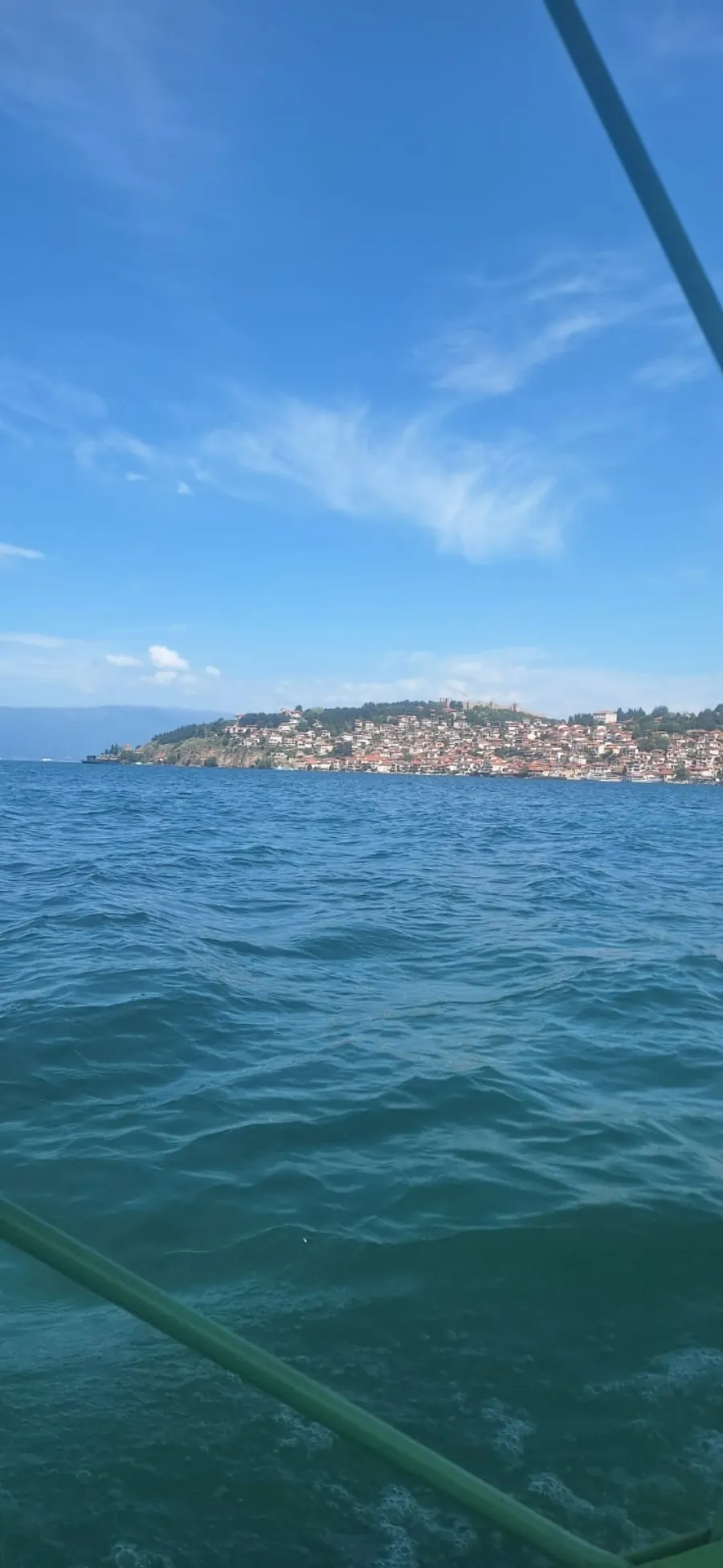 View of the Old Town of Ohrid from the lake — red roofs, Samuil's Fortress, and clear blue water