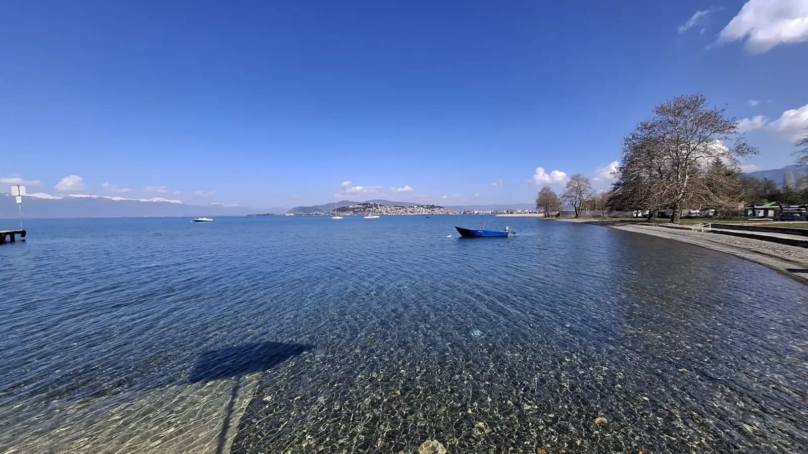 View of Kaj Divono beach on Lake Ohrid — calm water, a boat, and a panorama of the lake