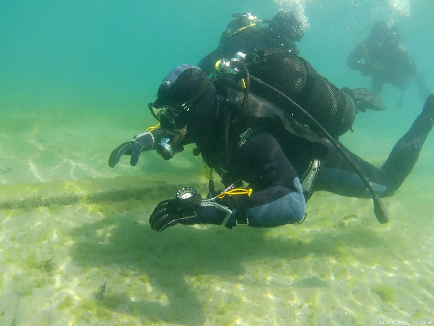 Underwater scene of scuba divers above the sandy floor of Lake Ohrid at Ljubaništa